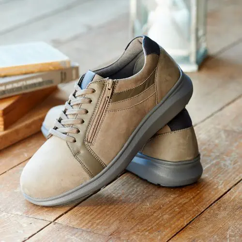 A pair of brown lace and zip trainers on a table