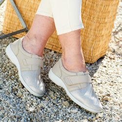 Someone sat down wearing a pair of beige strap trainers